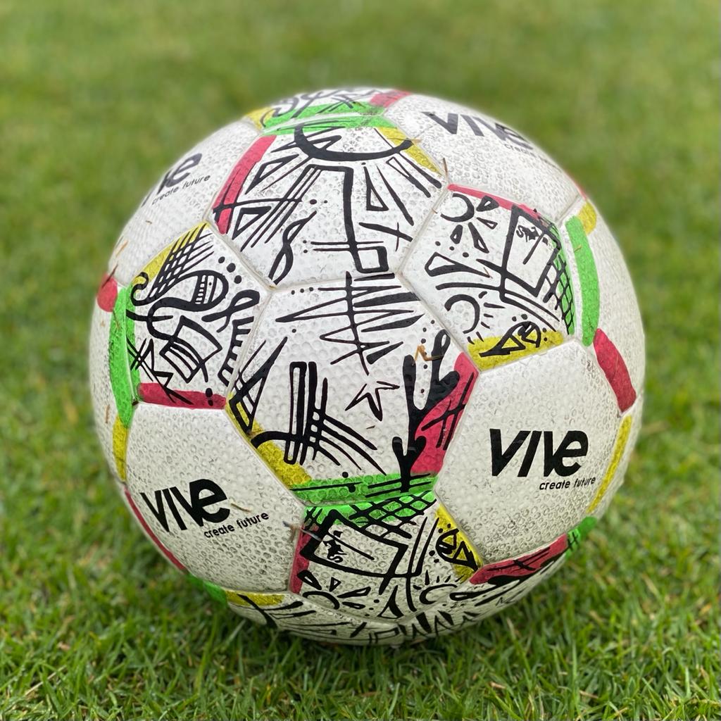 Campeones Size 5 Soccer Ball close up detail shot on soccer field - White color with Black artwork design with red yellow green trim from Vive